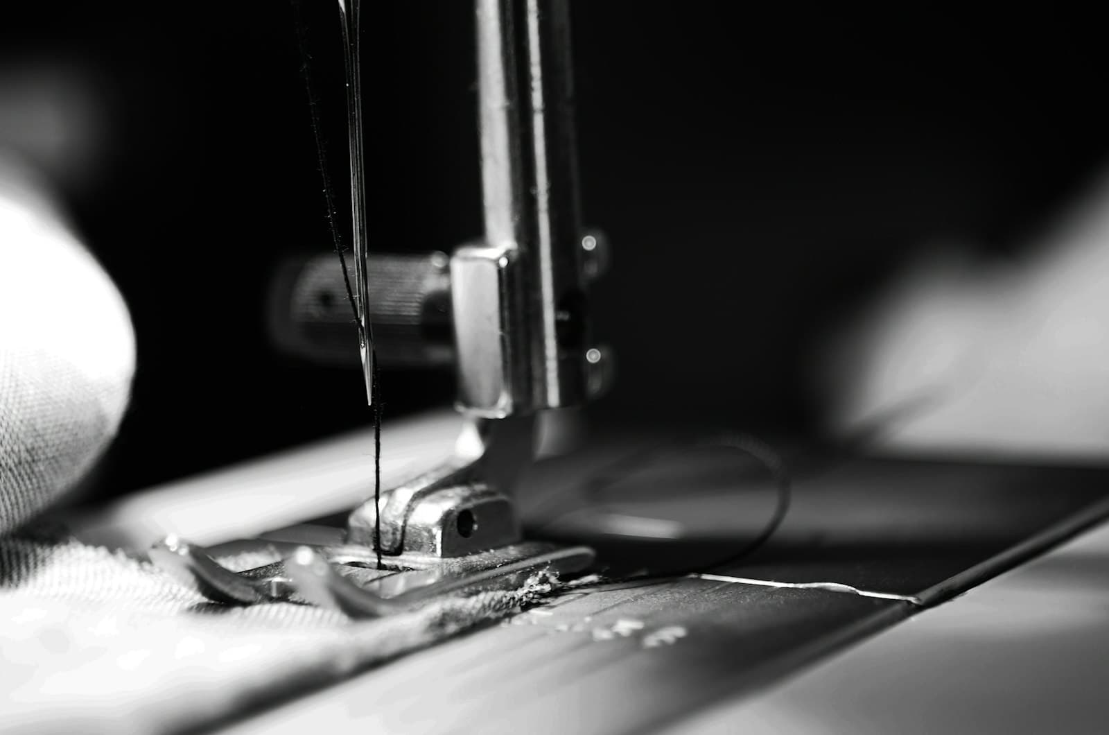 A sewing machine needle above fabric, black-and-white close-up